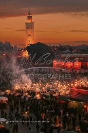 Image du Maroc Professionnelle de  Au coucher du soleil et même un peu avant la foule envahi la fameuse Place Jemaa El Fana qui se métamorphose en un gigantesque restaurant en plein air grâce aux nombreux stands et gargotes qui s'y installent sur ce lieu mythique au centre de la médina de Marrakech. Au fond le minaret de la Koutoubia, Samedi 26 Février 2005. (Photo / Abdeljalil Bounhar)

